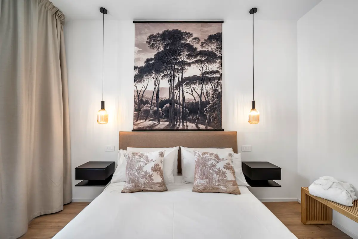 Dettaglio del letto con quadro decorativo e toni naturali in una suite dallo stile minimalista sul Lago di Garda.