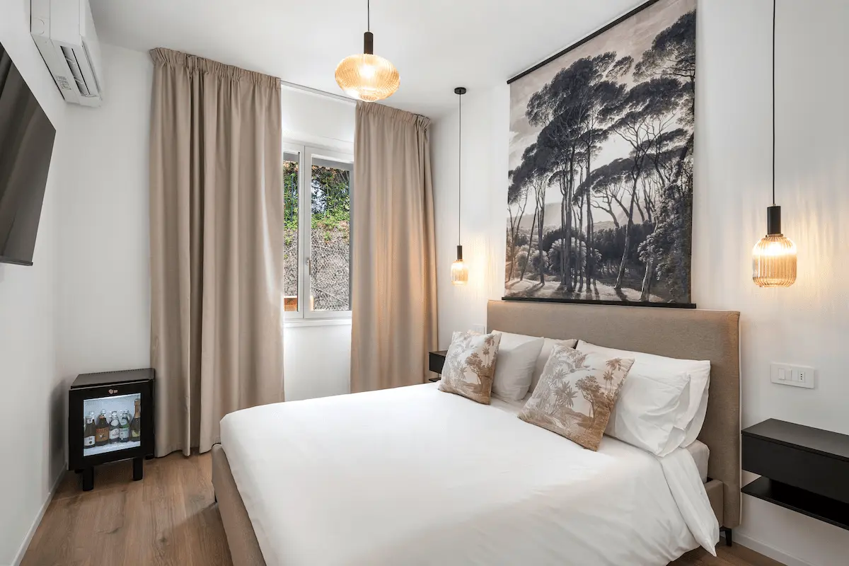 Camera essenziale al The View Lake Garda con letto matrimoniale, smart TV, minibar e quadro a parete, interni beige dallo stile minimal e rilassante.