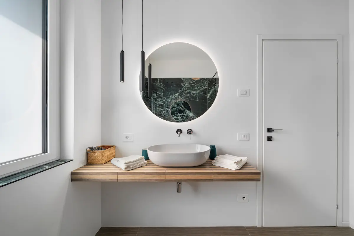 Bagno con lavabo moderno e finiture effetto marmo verde, in suite elegante con vista Lago di Garda.