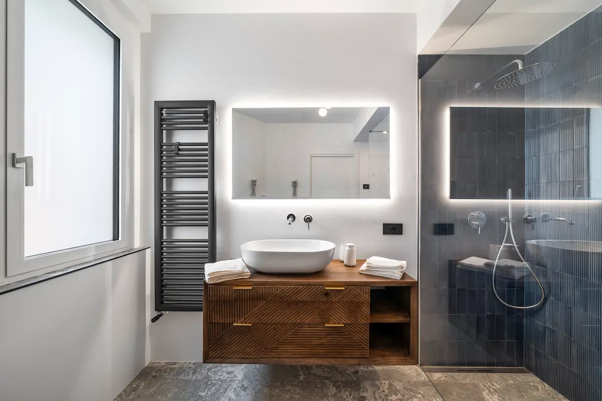 Bagno con lavabo moderno e specchio retroilluminato, suite di design al The View sul Lago di Garda.